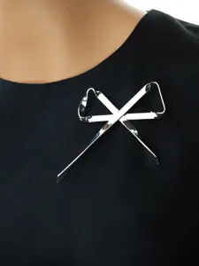Spilla minimalista con fiocco in nastro di metallo argentato, design geometrico elegante.