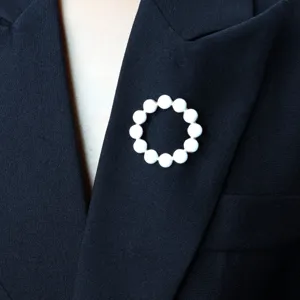 White beaded circle brooch detail shot, elegant enamel pin accessory for cardigan or scarf.