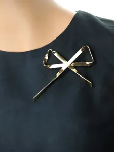 Primo piano dettagliato di un elegante accessorio spilla con fiocco in metallo dorato.