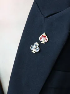 Close-up detail of asymmetric heart and club pearl brooch pin, elegant suit clothing accessory.