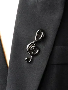 Close-up detail shot of a stylish black enamel treble clef brooch pin on a suit lapel.