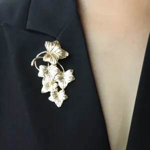 Vintage gold-tone ivy leaf brooch detail close-up, elegant clothing accessory for women.
