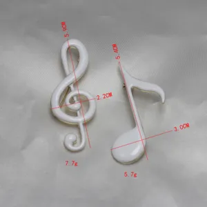 Detail shot of white enamel music note brooches, showing precise dimensions and lightweight design.