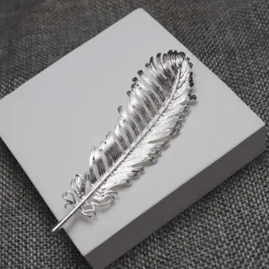 Detailed close-up of a delicate silver feather brooch, elegant metal accessory for clothes.