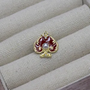Detailed shot of a stylish spade-shaped brooch with red enamel and white pearl accent.