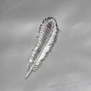 Silver feather brooch detailed shot, elegant lapel pin accessory for suits, dresses and hats.
