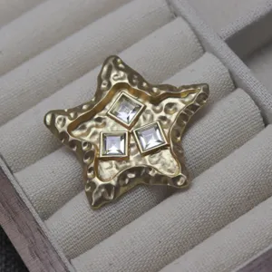 Detailed close-up of vintage lava-style gold-plated star brooch with three square crystals.