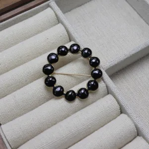Detailed close-up shot of a chic black beaded circular brooch and scarf buckle displayed neatly.