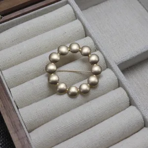 Matte gold dot circle brooch pin, elegant tambourine pattern clothing accessory for women.