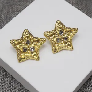 Closeup of vintage style gold molten star earrings featuring sparkling square rhinestone crystals.
