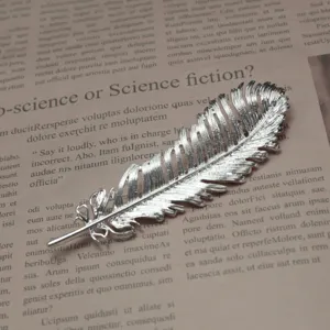 Detailed close-up view of silver feather brooch showing delicate metallic texture and fine details.