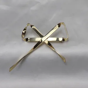 Dettaglio spilla fiocco nastro oro minimalista, elegante accessorio metallo per donne.