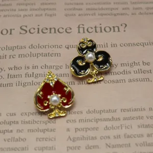 Detailed close-up of asymmetric spade and club brooch pins with pearls and gold finish.