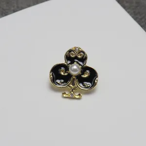 Detail shot of black enamel club brooch with central pearl and gold trim, stylish apparel pin.