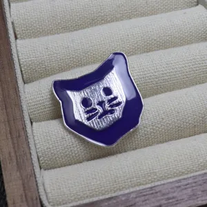 Primo piano dettagliato di un'elegante spilla smaltata gatto viola e argento sul velluto.