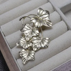 Vintage gold-toned metal ivy leaf brooch detail, elegant botanical clothing accessory for gifts.