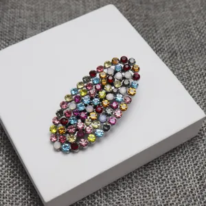 Detailed close-up of colorful rhinestone oval hair clip, sparkling crystal decorative barrette.