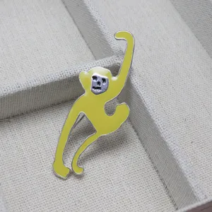 Primo piano di una graziosa spilla a forma di scimmia in smalto giallo con bordo argentato.