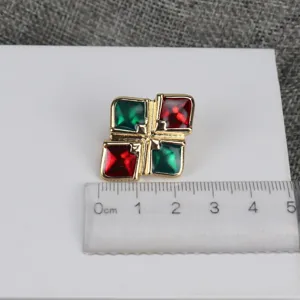 Detalle de pendientes barrocos vintage con cuadrados de esmalte rojo y verde y borde dorado.