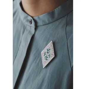 Diamond enamel brooch close-up, botanical floral design detail, stylish fashion accessory.
