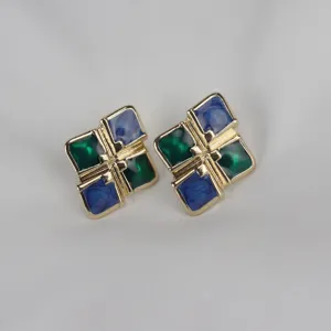 Primer plano de pendientes vintage de esmalte geométrico, detalle con tonos dorados y azul.