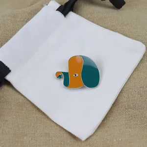Detailed shot of a cute abstract dog enamel brooch displayed on a white fabric pouch.