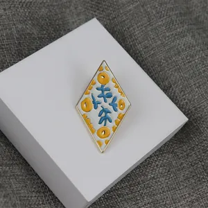 Detailed view of the diamond-shaped enamel brooch showing exquisite blue and yellow floral details.