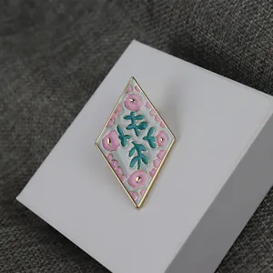Exquisite diamond-shaped enamel brooch featuring charming floral patterns and sleek metal trim.