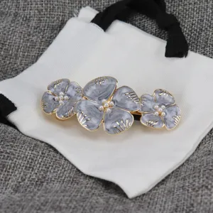 Vue détaillée de la pince à cheveux rétro en émail avec fleurs de perles et métal élégant.