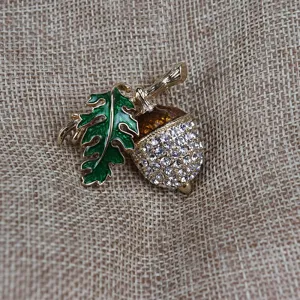 Dettaglio spilla ghianda strass smalto vintage che mostra cristalli scintillanti e foglia verde.