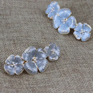 Vue rapprochée détaillée de pinces à cheveux florales en émail vintage et perles.