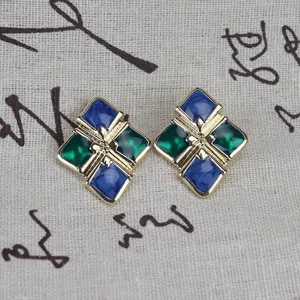 Primer plano de pendientes de tuerca esmaltados geométricos vintage de estilo barroco.