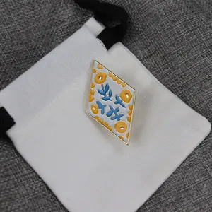 Close-up detail of the diamond-shaped enamel brooch with unique floral pattern and gold rim.