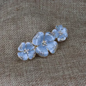 Détail de pince à cheveux fleur émail bleu, vue rapprochée accessoire barrette perle vintage.