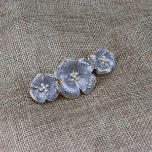 Détail de pince à cheveux fleur perle émail vintage, accessoire cheveux gris élégant.