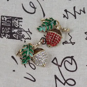 Spilla vintage in smalto a forma di ghianda con strass rossi e bianchi brillanti e foglie verdi.
