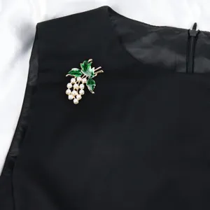 Pearl grape brooch detail view, vintage green enamel leaf pin on black fabric, elegant jewelry.
