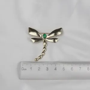 Vintage dragonfly alloy brooch with green enamel accent, detailed clothing accessory.