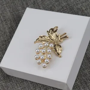 Vintage gold-tone grape brooch detail featuring elegant white faux pearls and leaf charms.