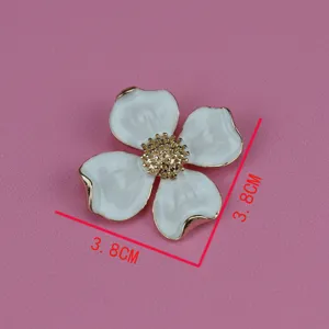 Vintage metal four-petal flower brooch featuring white enamel and elegant gold stamen.