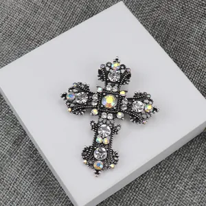 Gedetailleerde close-up van een vintage zilveren kruis broche versierd met sprankelende strass.