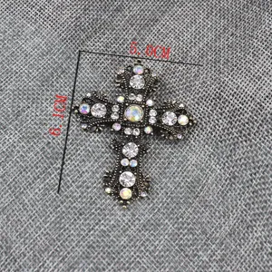 Gedetailleerde close-up van een vintage strass kruis broche en hanger in antiek goud.
