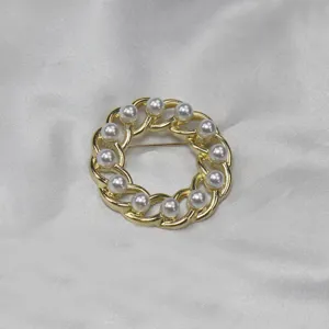 Vintage gold-tone chain circle brooch detail featuring classic white faux pearl decor.