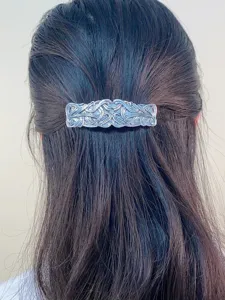 Vintage alloy engraved hair clip detail showing intricate retro metal pattern on dark hair.