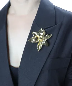 Gold metal flower brooch detail shot, elegant lapel pin jewelry for women blazers.