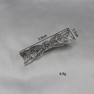 Detail view of the vintage silver bow hair clip, showing intricate filigree metal craftsmanship.