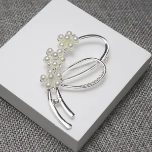 Detailed close-up of a silver pearl rhinestone flower brooch, perfect sweater suit accessory.