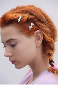 Detailed close-up shot of a sparkling rhinestone bow hair clip worn elegantly on braided hair.