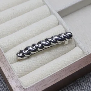 Close-up detail shot of a silver twisted spring hair clip inside a jewelry box slot.