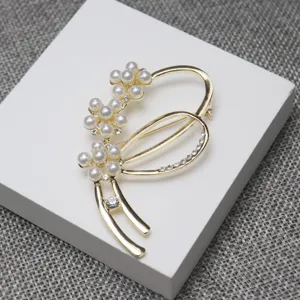 Detailed shot of gold-tone pearl and rhinestone brooch, elegant floral design for suit sweaters.